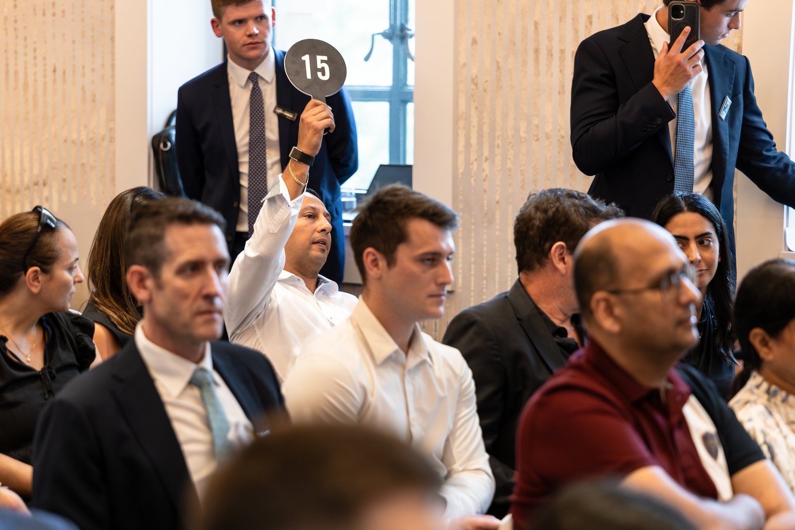 Left: paddle fifteen, in. Right: an agent on two phones at once — the shot that says more about how this business works than any wide ever could.